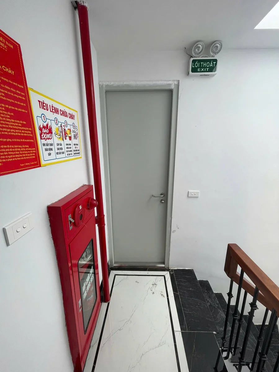 Hành lang cầu thang nhà cho thuê có nội quy, tiêu lệnh chữa cháy, hộp chữa cháy kèm nút ấn báo cháy, đèn EXIT và đèn chiếu sáng sự cố trên cửa